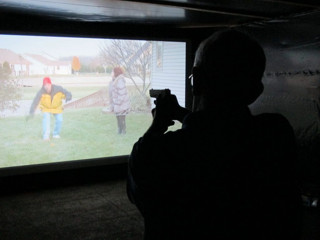 Mark Tulloch, of Kettering, Ohio, takes aim in a firearms training simulator at the Clark County Fair on Wednesday, July 26, 2017, in Springfield, Ohio. The county sheriff rented the simulator to offer as a free exhibit, hoping it will help the public better understand how quickly officers must decide whether to use lethal force. (AP Photo/Kantele Franko)